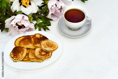tea and pancakes on the background of beautiful pions.