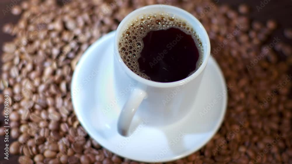 A cup of steaming hot coffee standing on arabica beans A cup of steaming hot coffee standing on arabica beans