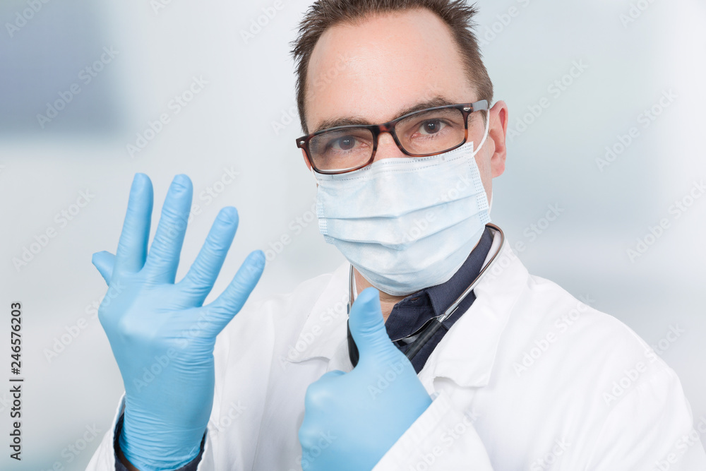 Ein Arzt mit Mundschutz zieht sich hygienische Handschuhe an Stock Photo |  Adobe Stock