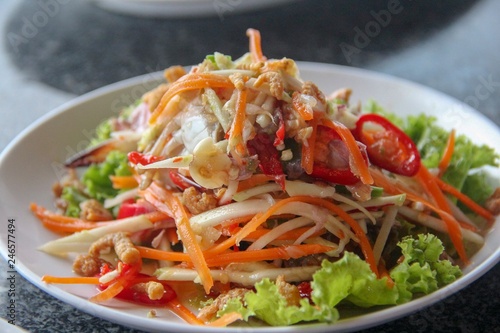 Spicy green papaya salad (Som Tam) mixed with vegetables, fresh blue crab and Thai herbs in Thai style 