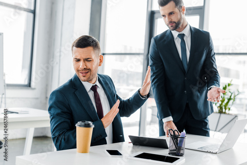 Принти на полотні upset businessman turned away from coworker in modern office