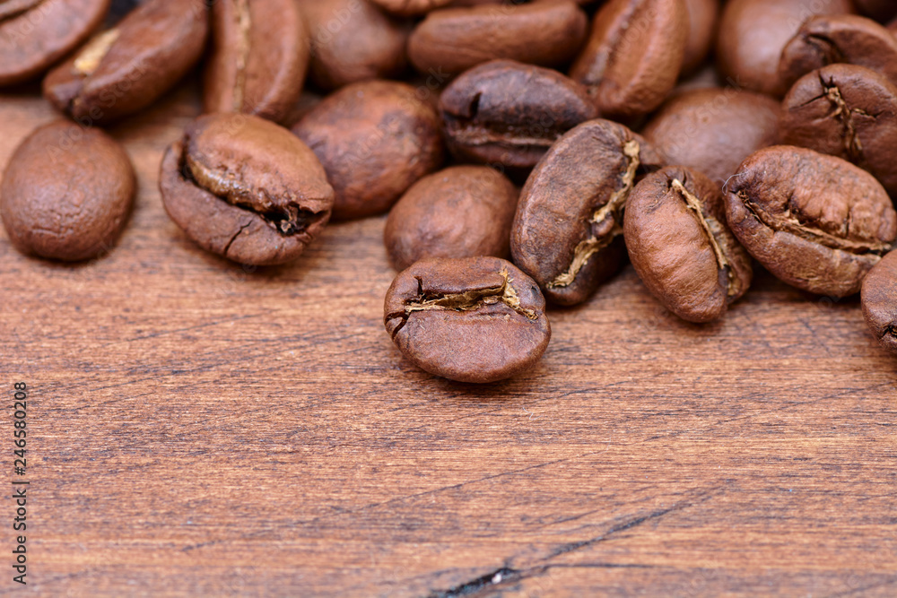 Fototapeta premium coffee beans on a wooden background scattered