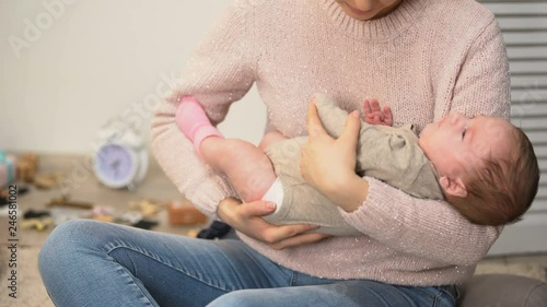 Young female putting cute newborn baby girl to sleep, infant colic relieving photo