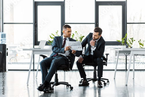 handsome businessmen reading business newspaper while sitting in modern office