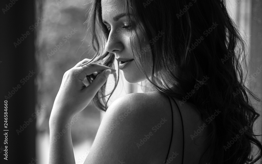 Φωτογραφία Black white portrait of young woman in elegant silk black dress lookingto a city