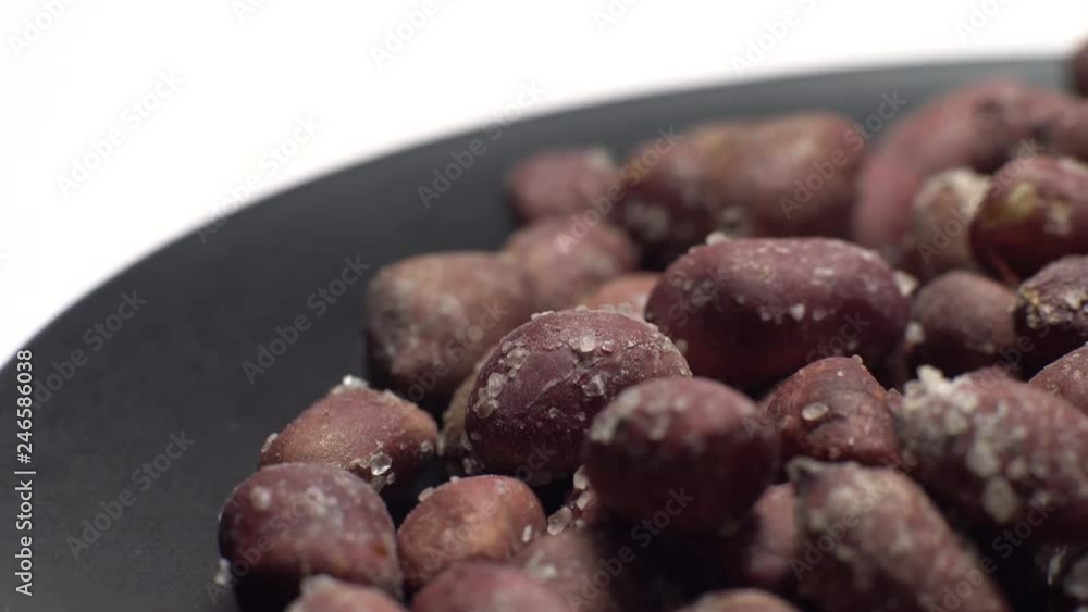 Raw unpeeled peanuts fried with salt. Rotation. Snack closeup. Peanuts in a bowl. Selective focus. Isolated on white. Studio shot. Healthy food concept. Raw unpeeled peanuts fried with salt. Rotation. Snack closeup. Peanuts in a bowl. Selective focus. Isolated on white. Studio shot. Healthy food concept.