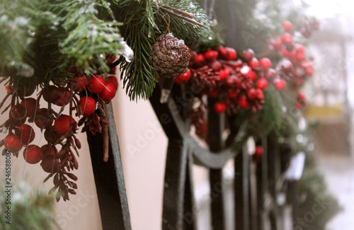 Christmas outdoor decoration: garland of green fir branches, pine cones and bright red berries 