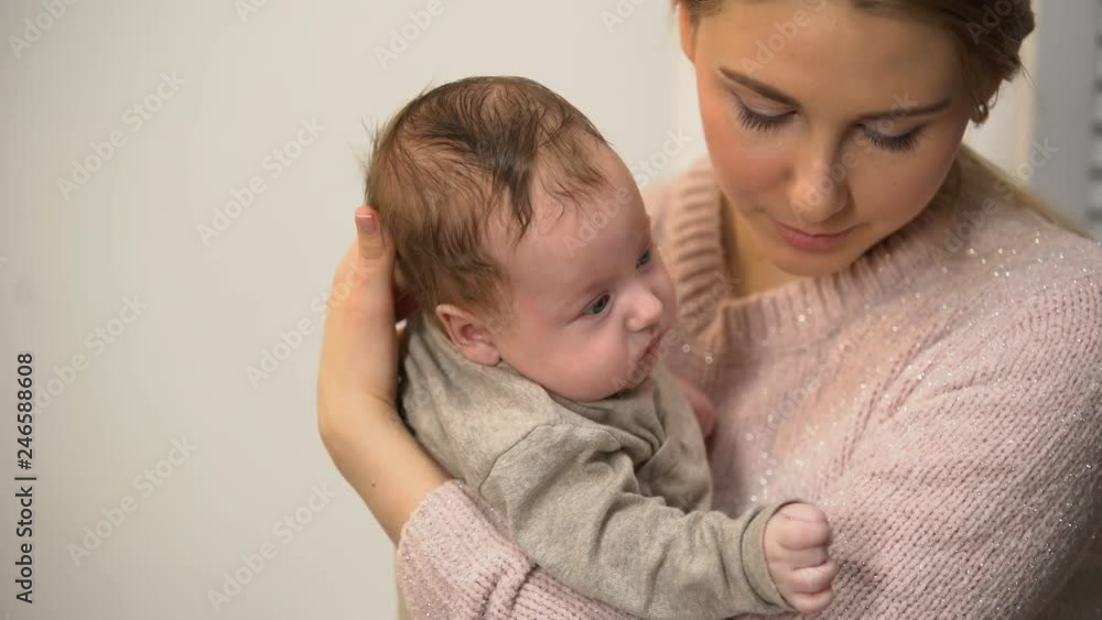 Attentive female babysitter holding little adorable baby and talking to him Attentive female babysitter holding little adorable baby and talking to him