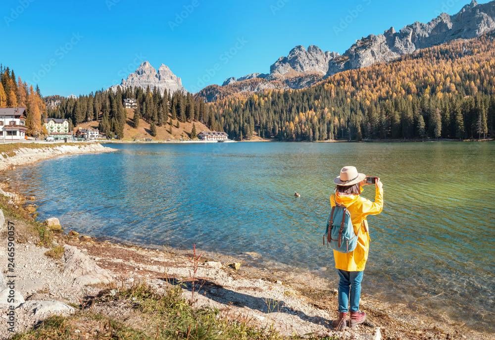 Traveler Woman use mobile phone to take amazing photos of a Misurina mountains lake