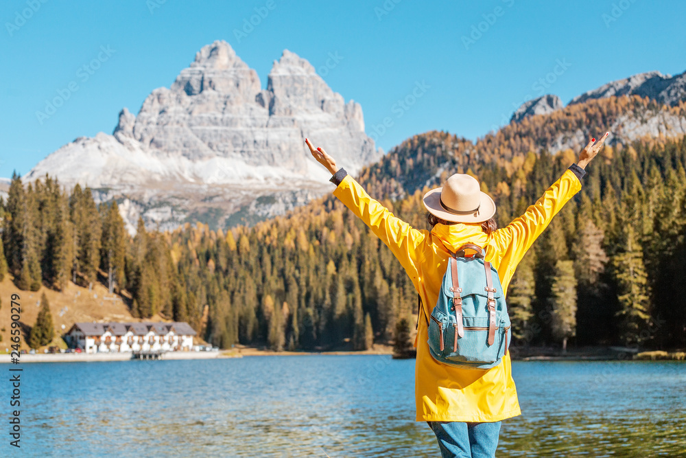 Φωτογραφία Young happy asian woman with yellow jacket travel at the famous tourist destination in Dolomites mountains - Misurina lake during autumn