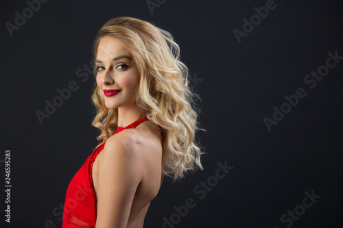 beautiful young girl with graceful figure in a red dress on a black background