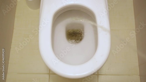 Man peeing to toilet bowl in restroom. Stream of urine flows into the bowl photo