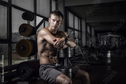 Fitness guy holding huge dumbbell in old rusty gym. Shallow depth of field