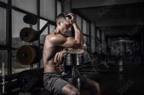 Fitness guy holding huge dumbbell in old rusty gym. Shallow depth of field