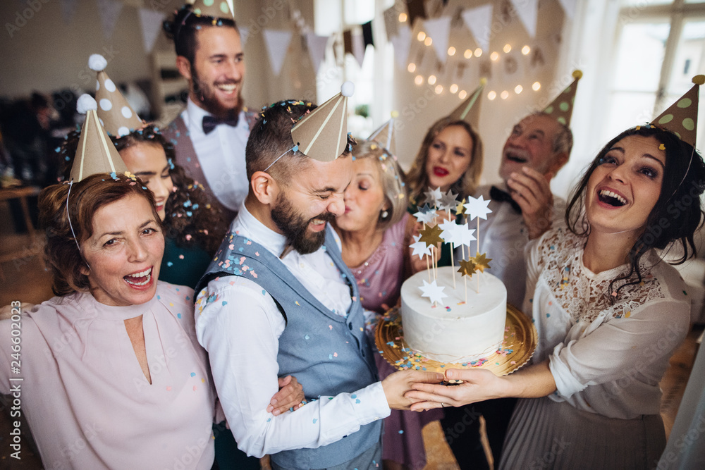 A portrait of multigeneration family with a cake on a indoor birthday party. A portrait of multigeneration family with a cake on a indoor birthday party.