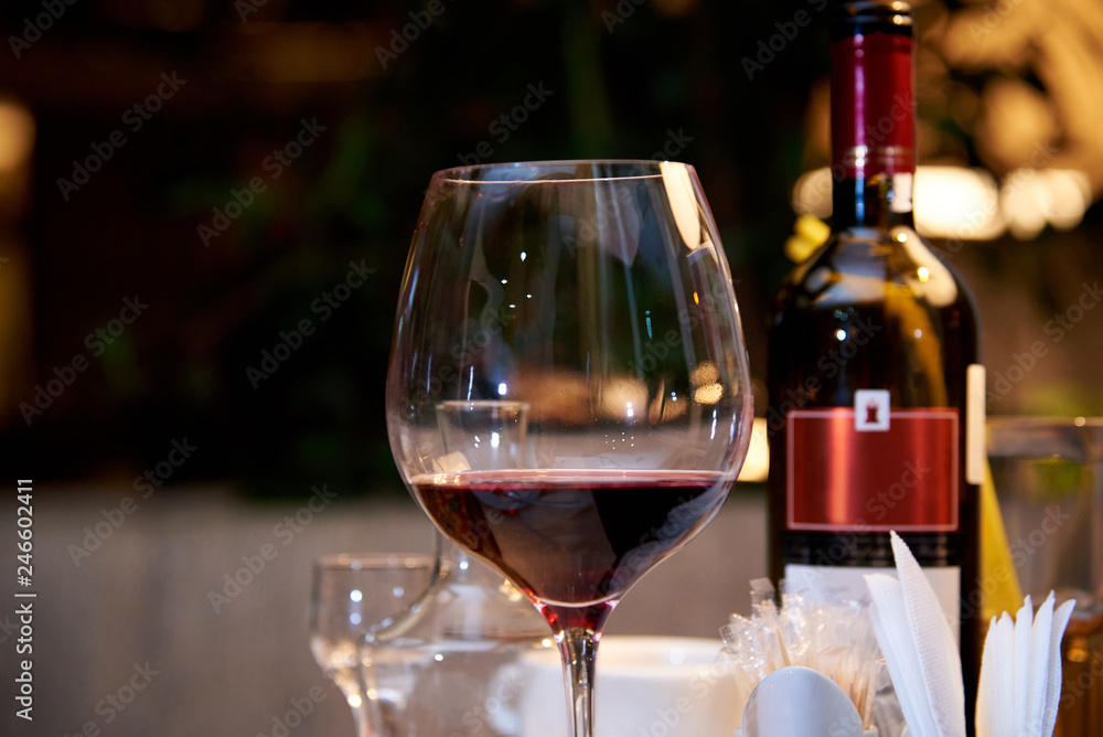 A glass of red wine on a served table in a restaurant.