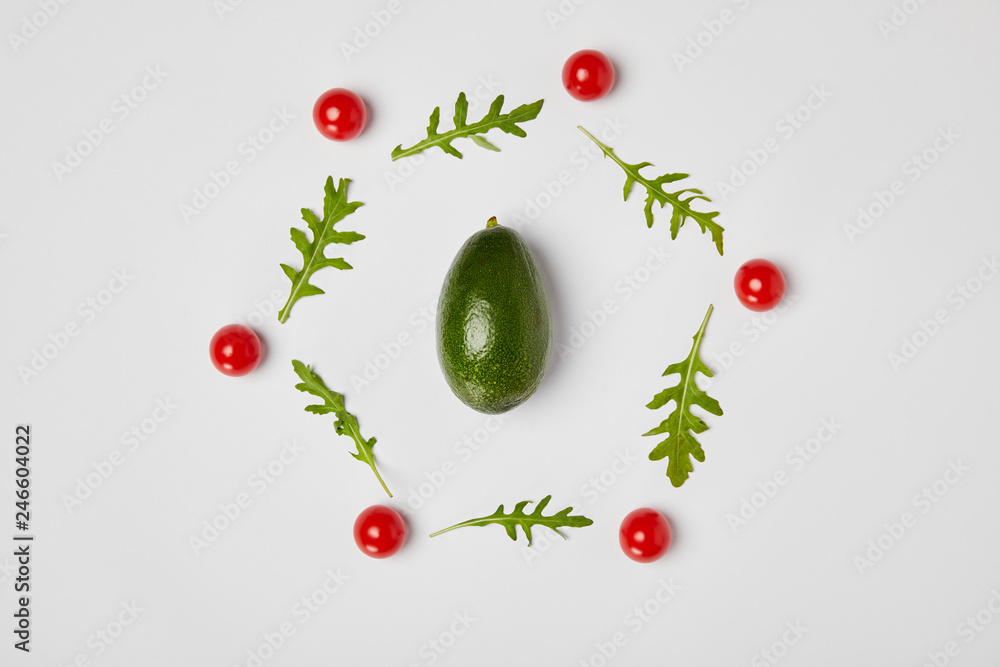 top view of avocado, arugulas leaves and cherry tomatoes on grey background top view of avocado, arugulas leaves and cherry tomatoes on grey background