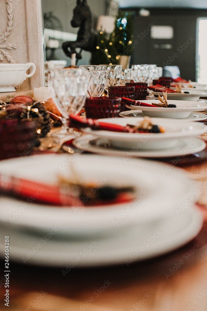 .Detail photograph of a table prepared and decorated for a party diner. Autumnal and festive decoration, with wood pineapples, candles, fruits and red colors. Lifestyle. Food photography