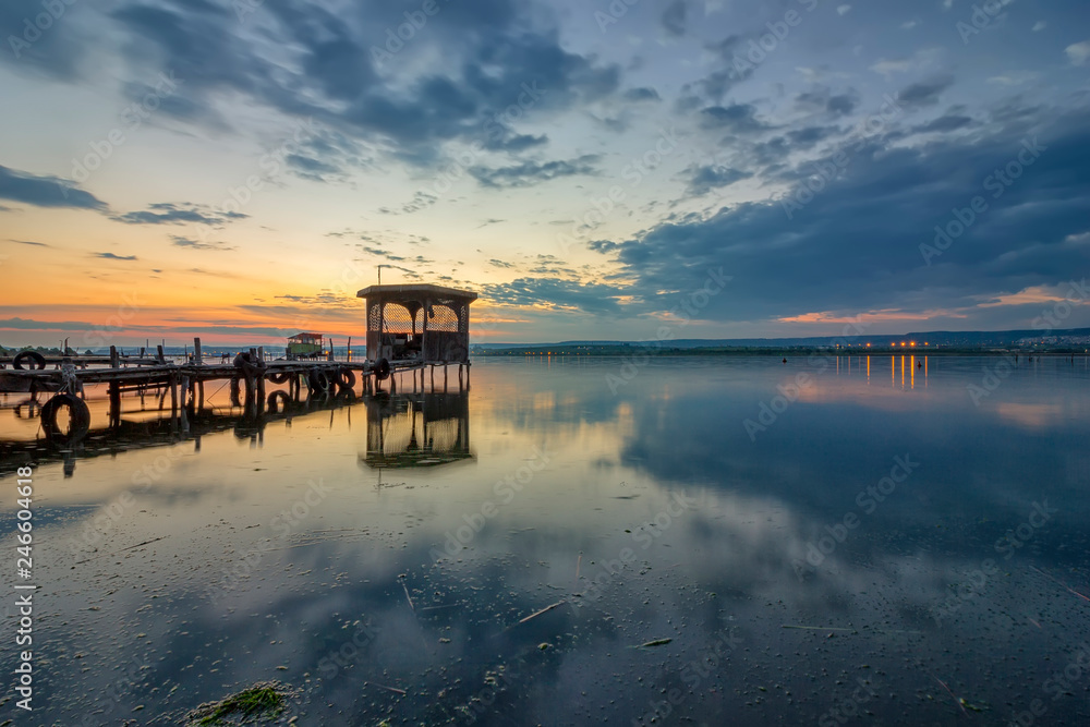 Exciting long exposure landscape on a lake with a wooden pier and gazebo in the end.