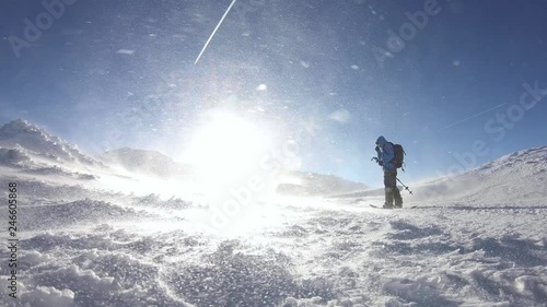 Man ascending on splitboard with climbing skins defying severe blizzard