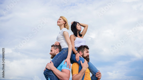 Enjoying themselves. Happy men piggybacking their girlfriends. Loving couples enjoy fun together. Loving couples having fun activities outdoor. Playful couples in love smiling on cloudy sky