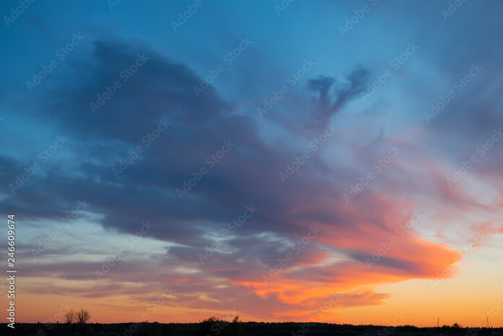Mystical sunset clouds over the countryside in blue and orange tones