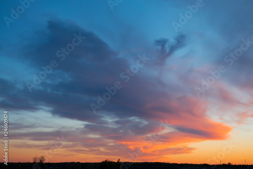 Mystical sunset clouds over the countryside in blue and orange tones © Lenaika