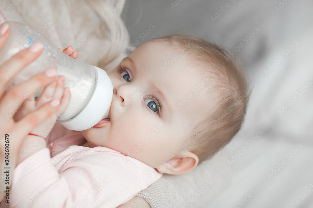Young mother feeding her little cute baby daughter with bottle of child formula. Woman with her newborn baby at home. Mom taking care of a child. Alternative to breast feeding. Young mother feeding her little cute baby daughter with bottle of child formula. Woman with her newborn baby at home. Mom taking care of a child. Alternative to breast feeding.