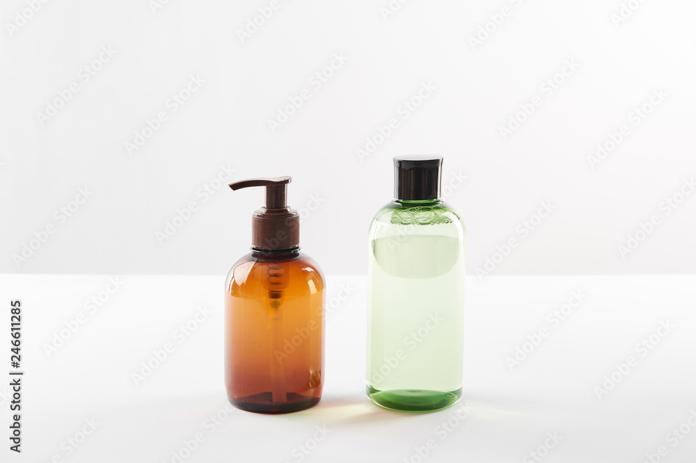 Cosmetic dispenser with lotion and bottle of serum on white surface Cosmetic dispenser with lotion and bottle of serum on white surface