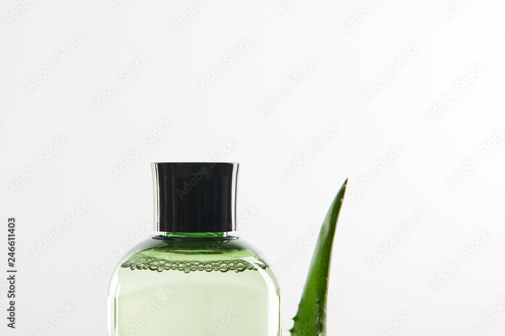transparent cosmetic bottle and aloe vera leaf on white background
