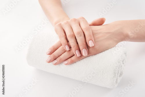 Partial view of female hands on terry soft rolled towel on white background