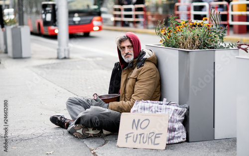 Quadro su tela Homeless beggar man sitting outdoors in city asking for money donation