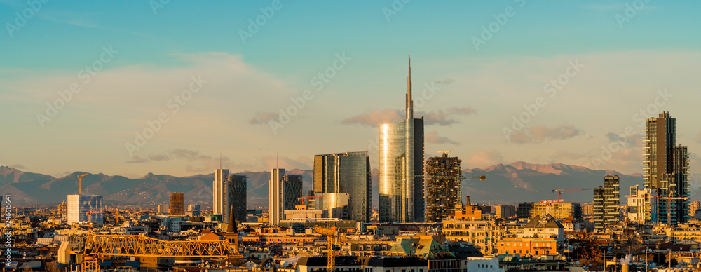 Aerial view of Milan skyline at sunset with alps mountains in the background.