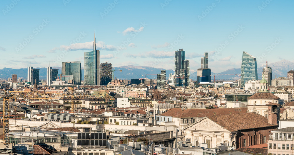 Fototapeta premium Milan skyline. Large panoramic view of Milano city, Italy. The mountain range of the Lombardy Alps in the background. Italian landscape.