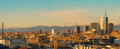 Aerial view of Milan skyline at sunset with alps mountains in the background.