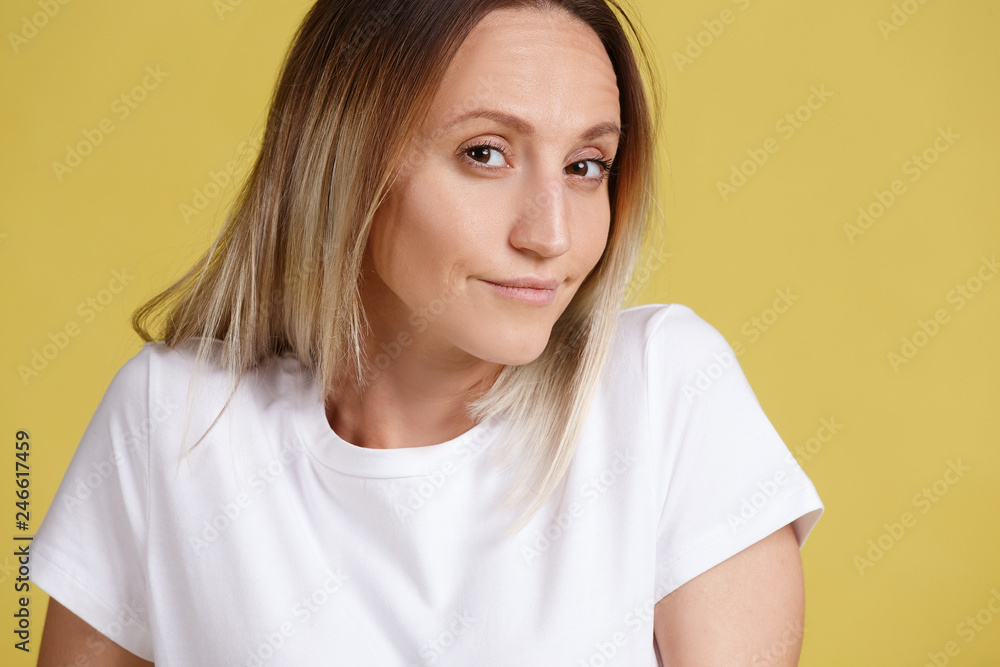 Doubting young pretty woman shrugs and looks absently into the frame on a yellow background. Young girl doubts which gift to choose for the New Year. Advertising space Doubting young pretty woman shrugs and looks absently into the frame on a yellow background. Young girl doubts which gift to choose for the New Year. Advertising space