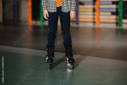 Partial view of boy in roller skates standing in roller rink