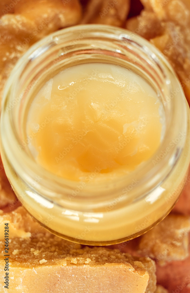 Hand cream or lip balm in a glass jar. Natural organic cosmetics with honey, wax and oils Hand cream or lip balm in a glass jar. Natural organic cosmetics with honey, wax and oils