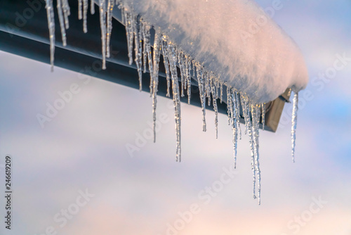 Snow covered roof with row of icicles against sky