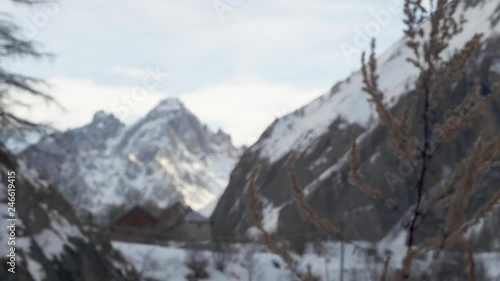 Close up of tree focus pulling to a winter scene with large mountains in the French Alps photo