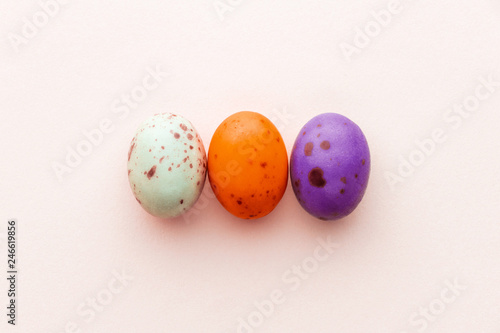 Halloween candy chocolate eggs on a pastel pink background, creative flat lay halloween concept, top view