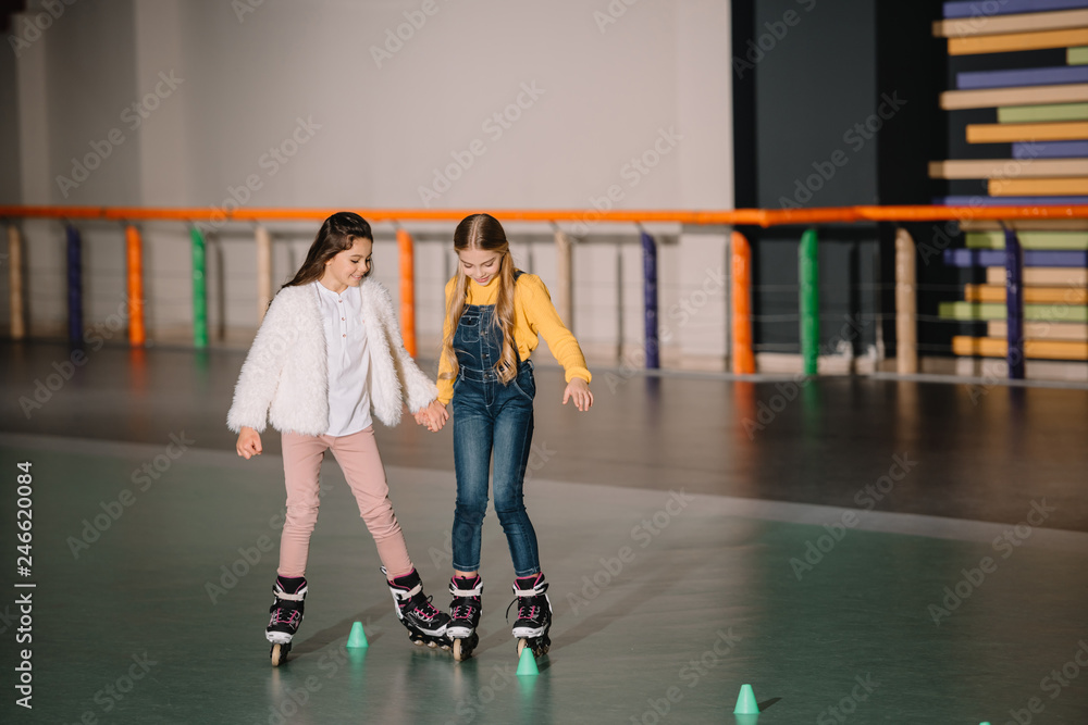 Beautiful kids practicing rolling skating while holding hands