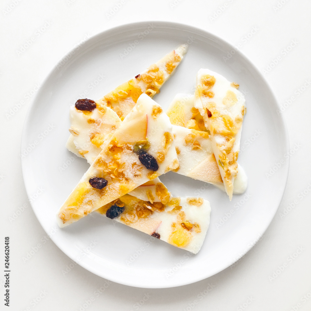Homemade healthy frozen muesli yogurt bark with orange and apple, top view close up