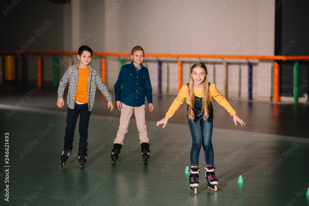 Fototapeta premium Smiling kids in roller skates training on rink