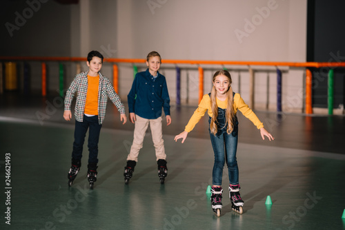 Smiling kids in roller skates training on rink