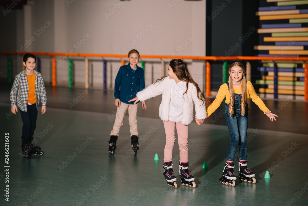 Fototapeta premium Friends in roller skaters laughing and holding hands