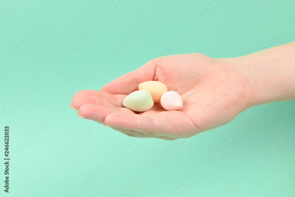 Woman hand holding beauty sponge on green background. Woman hand holding beauty sponge on green background.