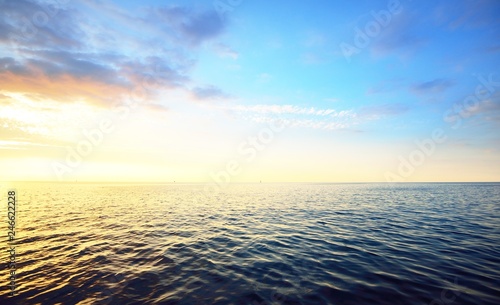 Sunset in a cloudy sky over open Baltic sea with veri distant ship silhouettes. photo