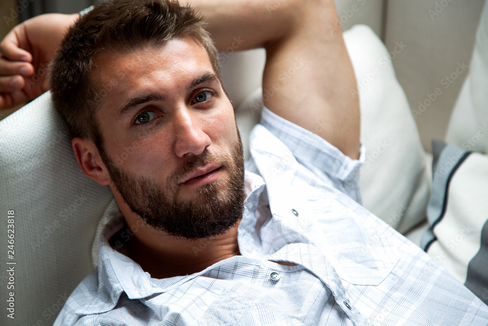 Obraz premium Attraktiver bärtiger Mann entspannt sich auf der Couch
