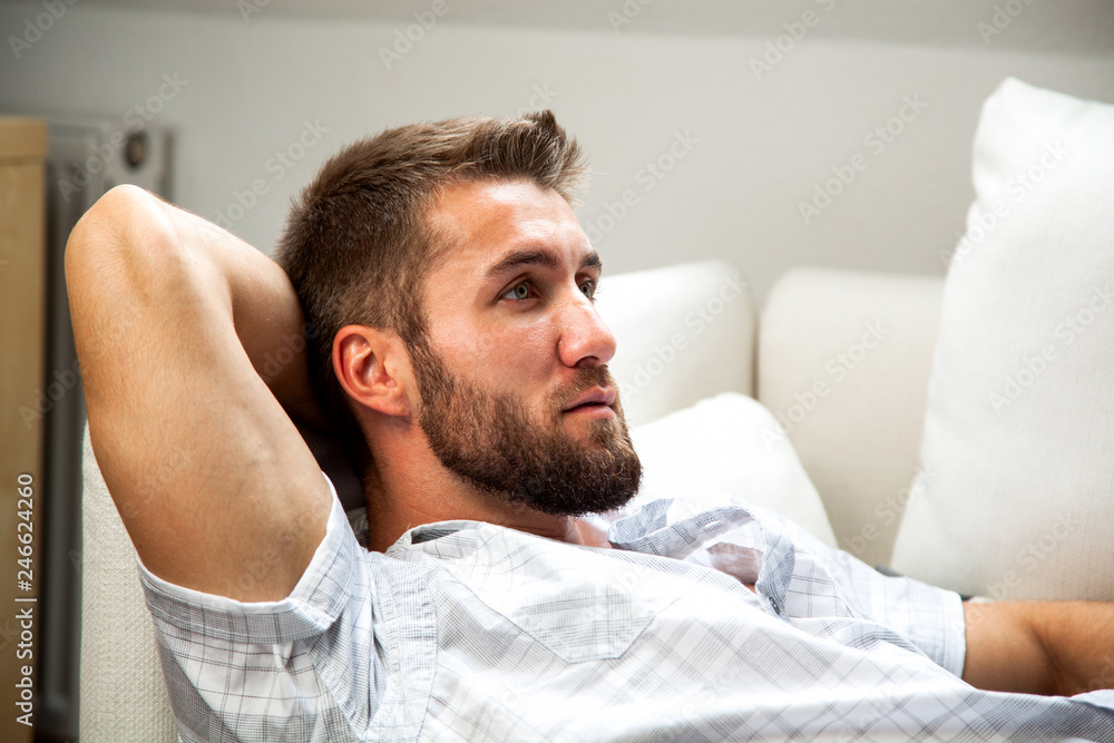 Obraz premium Attraktiver bärtiger Mann entspannt sich auf der Couch